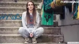 Kira mit verängstigtem Gesichtsausdruck und offenem Mund vor grünem Graffiti-Wandbild