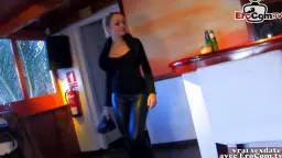 Blonde MILF mit Pferdeschwanz und tiefem Dekolleté lächelt verführerisch in einer holzgetäfelten Sauna