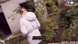Mann mit schwarzem Hoodie macht Selfie vor Hochhausruine und Zaun