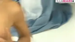 Nacktes schwarzhaariges Babe in schwarzen Stiefeln kniet lasziv auf weißem Studioboden vor blauem Sofa