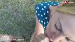 Blonde Frau im gepunkteten Kleid kniet auf Wiese